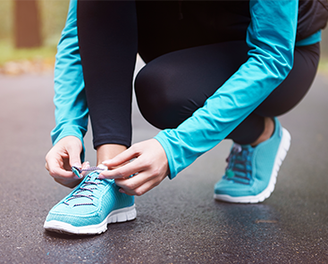 Image of woman bending down and doing up shoe laces on trainers